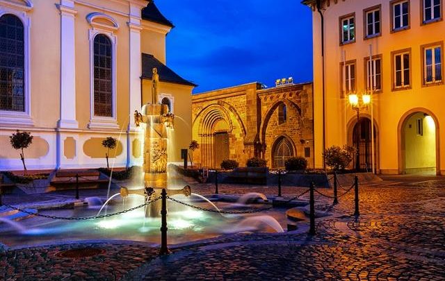 Zu sehen ist der Erkenbertbrunnen auf dem Rathausplatz in Frankenthal (Pfalz). Das Bild wurde bei Abend-Dämmerung aufgenommen.en