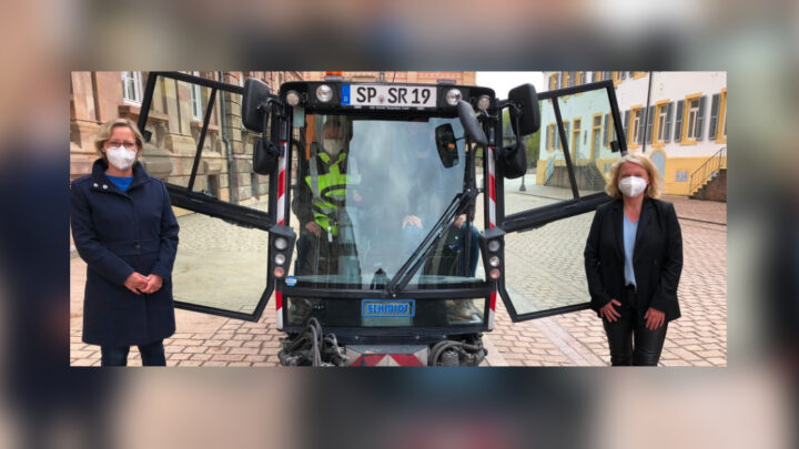 Zu sehen ist eine Kehrmaschine auf dem Domplatz in Speyer. Links nebendran steht Bügermeisterin Frau Seiler und rechts Frau Selg (Beigeordnete für Digitalisierung)