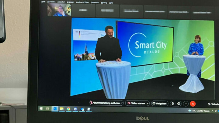 Ein geöffneter Laptop mit der Ansicht einer Videokonferenz, auf dem Bild stehen zwei Personen in einem TV-Studio der Regionalkonferenz.